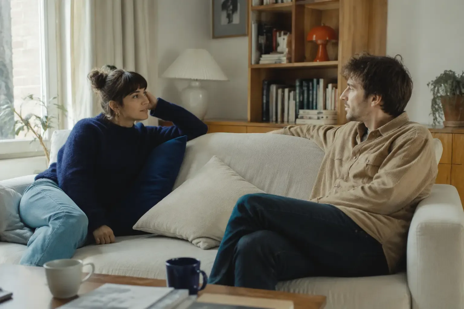 Two people talking together on a sofa at home.