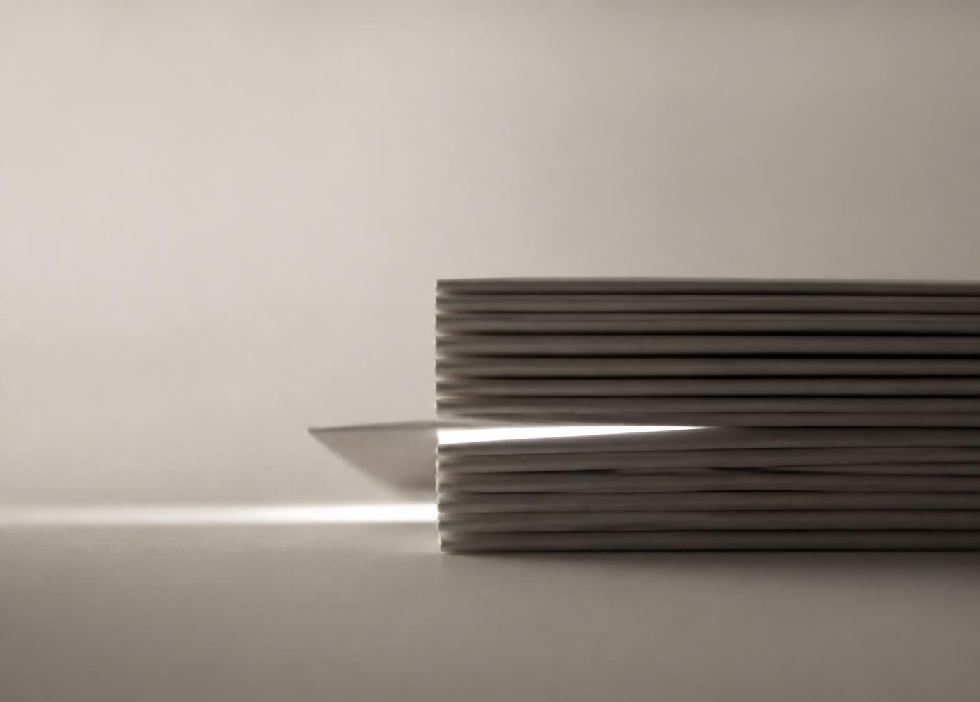 A stack of plain paper sheets seen edge-on, one pulled out and light falling into the gap