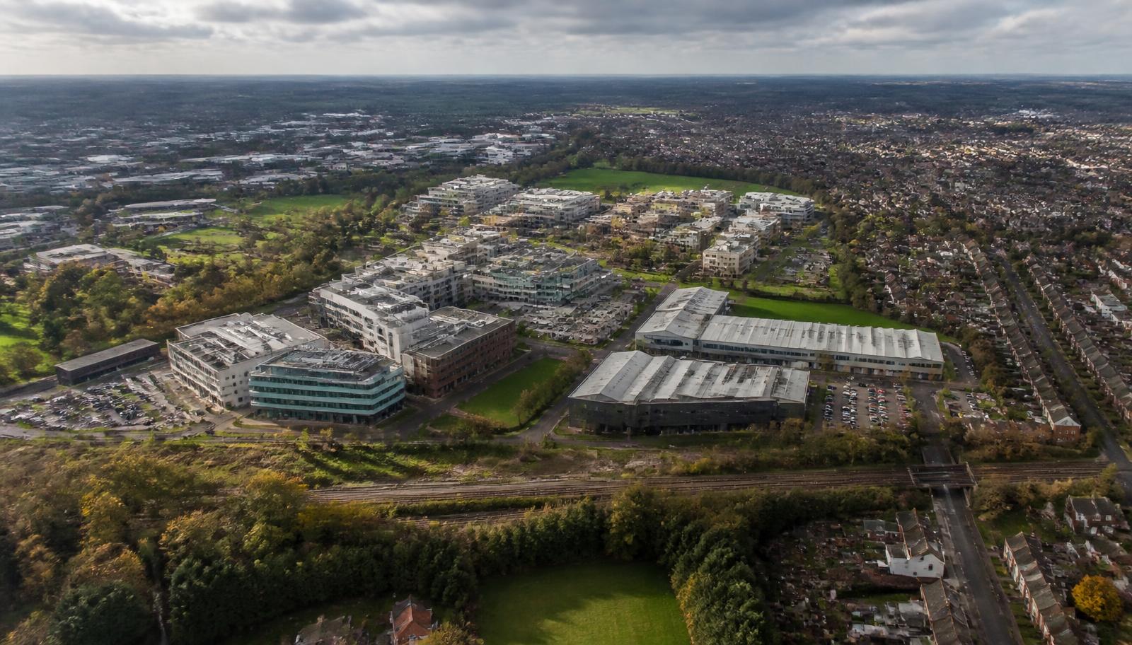 High oblique aerial view of a British town where university buildings, light industry, housing, railway and open landscape meet
